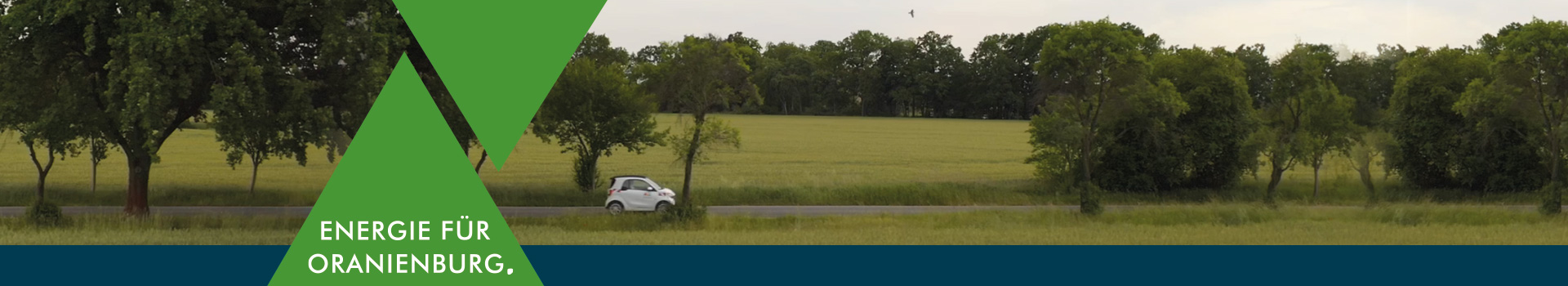 Grafik mit gr&uuml;nem Dreieck und dem Claim &sbquo;Energie f&uuml;r Oranienburg. &lsquo; vor einem E-Auto das eine Landstra&szlig;e langf&auml;hrt.