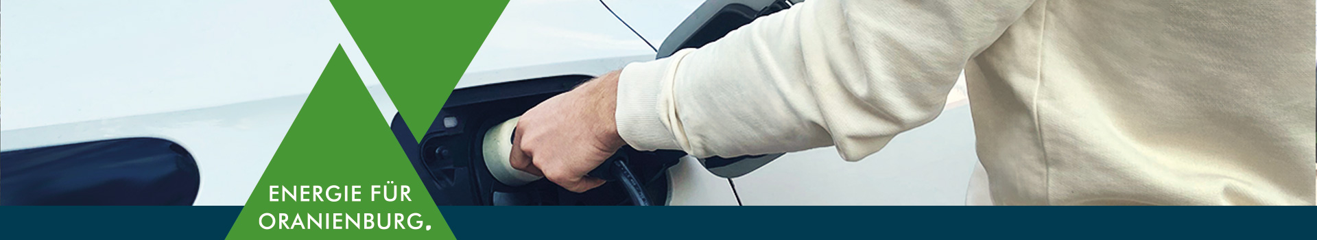 Grafik mit gr&uuml;nem Dreieck und dem Claim &sbquo;Energie f&uuml;r Oranienburg. &lsquo; vor einer Hand die ein E-Auto zum laden anschlie&szlig;t.